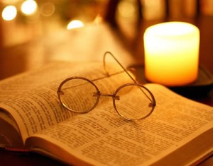 libro e occhiali al lume di candela